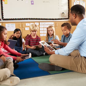 Teachers and students on rug in classroom.